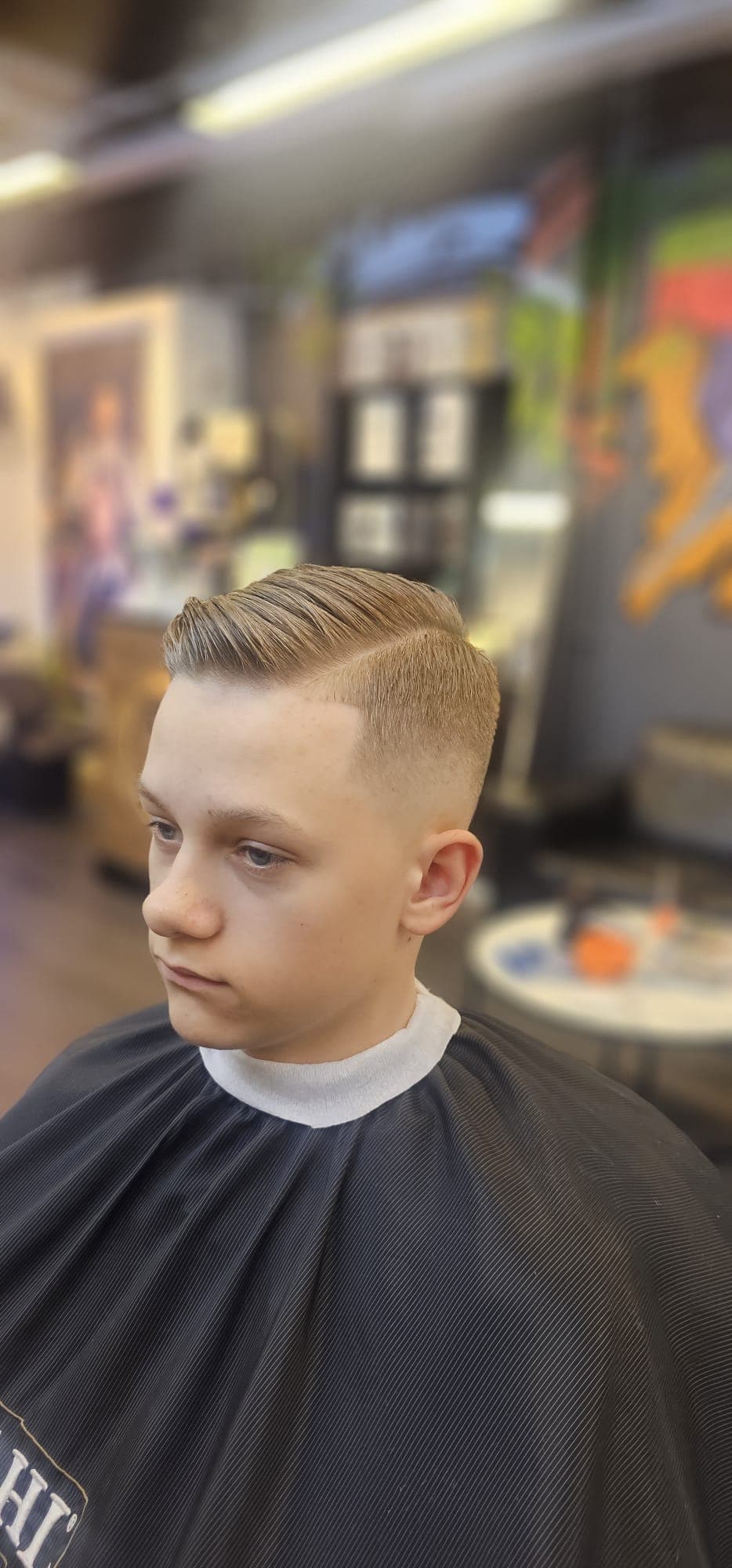 Ung kund med sidbena och skin fade, håret kammat åt sidan